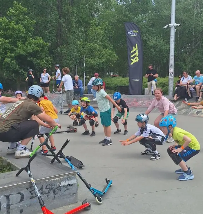 An instructor and helmeted participants warm up together at the Warsaw skatepark.