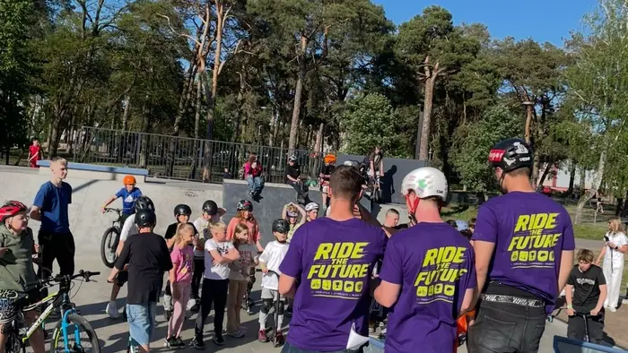 The crew in purple Ride The Future shirts stands in front of participants at the Ostrołęka skatepark.