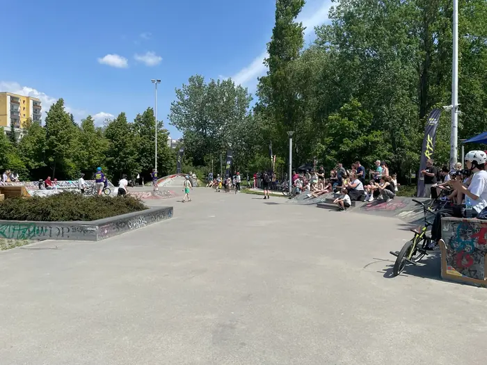 A wide view of the Ursynów skatepark with spectators beside the obstacles and Ride The Future flags.